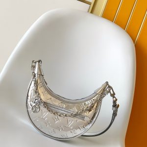 LOOP Handbag Silver Patent Leather This small Loop handbag from the LV Ski collection draws inspiration from the brand's iconic 1892 metal trunk. It features Monogram Miroir effect on embossed coated canvas, infusing traditional aesthetics with a retro-futuristic flair.The adjustable leather strap and detachable chain provide versatile options for carrying essentials and a long wallet during day-to-night outings. Dimensions: 13 x 6 x 23 cm